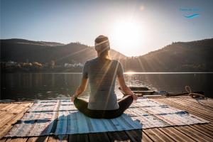 Eine Frau, die auf einem Dock sitzt, in einer Yoga-Pose auf dem Wasser. in der Unterkunft Canto Zêzere, Barragem de Castelo do Bode in Cernache do Bonjardim