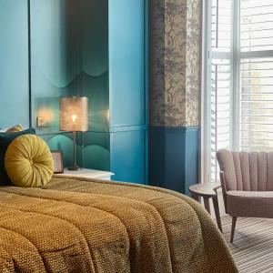 a bedroom with blue walls and a bed and a chair at The Southern Belle in Brighton & Hove