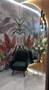 a living room with a green chair and a floral wall at APARTAMENTOS SAN NICOLAS in Adra