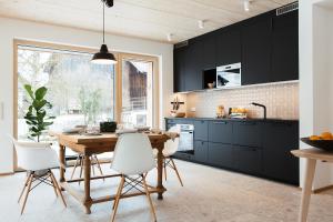 キーミングにあるFerienhaus Schmidhuberのキッチン(黒いキャビネット、木製テーブル、椅子付)