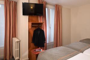 ein Schlafzimmer mit einem Bett und einem TV an der Wand in der Unterkunft Timhotel Paris Gare Montparnasse in Paris