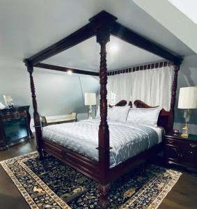 a bedroom with a canopy bed and a television at 1000 Islands Bed and Breakfast-The Bulloch House in Gananoque