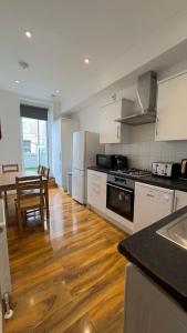 cocina con armarios blancos y suelo de madera en Kensington Guest Rooms 98, en Londres