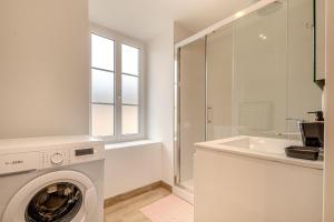 een witte wasruimte met een wasmachine en een wastafel bij Le Plaidoyer in Limoges