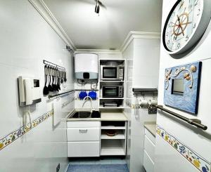 una cocina con armarios blancos y un reloj grande en la pared en Holibai, Parruliña, Estudio Con Terraza, Piscina, Parking Wifi, en Baiona
