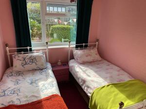 two beds in a room with a window at LetAway - Tom's Cabin, Staithes in Staithes