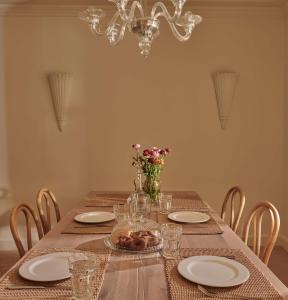 a dining room table with plates and a chandelier at Aghioti in Agios Nikitas +19 photos