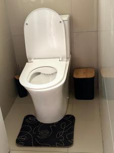 a white toilet in a small bathroom with a black rug at A home with a heart. in Durban