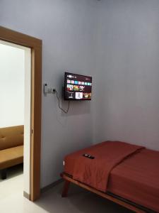 una camera con letto e TV a schermo piatto a parete di De'kost & homestay tegal a Lebaksiu