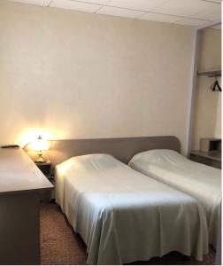 une chambre d'hôtel avec deux lits et une lampe dans l'établissement Hôtel Restaurant De La Mare, à Avrigny