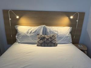 een bed met witte kussens en een houten hoofdeinde bij Living PDL 2 in Ponta Delgada