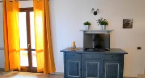 einen TV auf einem Schrank in einem Zimmer mit Vorhängen in der Unterkunft I fiori di Alberese in Alberese
