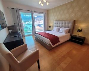 um quarto com uma cama, uma secretária e uma cadeira em Nova Madeira Apartment Machico em Machico