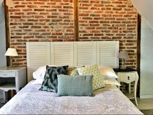 - une chambre avec un mur en briques et un lit avec des oreillers dans l'établissement Maison Rocher, à Ségur-le-Château