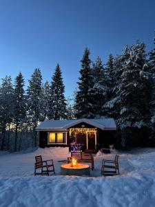 una cabina nella neve con un focolare di Gemuetliches Blockhaus im Wald ad Auktsjaur