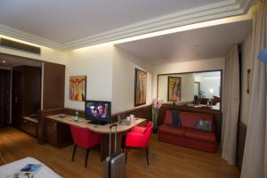 Habitación con escritorio, ordenador y sofá rojo. en As Hotel Cambiago, en Cambiago