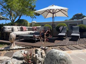 eine Terrasse mit einem Sofa, einem Sonnenschirm und Stühlen in der Unterkunft Kaya La Provence in Kapstadt
