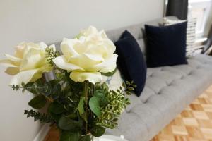 wazon z białymi kwiatami przed kanapą w obiekcie Comfortable stay in the heart of downtown Montreal w Montrealu