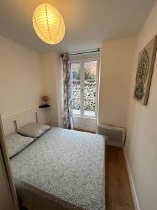 a small bedroom with a bed and a window at Le spacieux in Aurillac