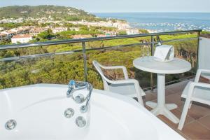 a bath tub on a balcony with a table and chairs at Hotel Garbi in Calella de Palafrugell