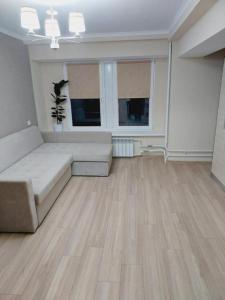 a living room with a couch and two windows at Квартира на Ботанике in Chişinău