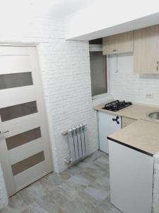 a white kitchen with a sink and a stove at Квартира на Ботанике in Chişinău +5 photos