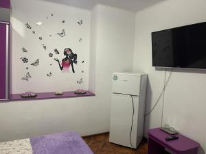 a room with a refrigerator and a tv with butterflies on the wall at CAMERE de INCHIRIAT LA TUGUIATA in Buşteni