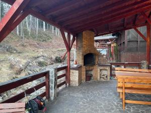 an outdoor patio with a brick oven and a wooden bench at CAMERE de INCHIRIAT LA TUGUIATA in Buşteni