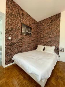 a bedroom with a brick wall and a white bed at Studio & Coworking Thème Factory A in Morsang-sur-Orge