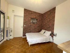 een slaapkamer met een bakstenen muur en een bed bij Studio & Coworking Thème Factory A in Morsang-sur-Orge