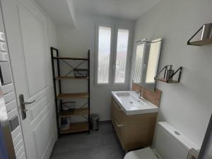 a white bathroom with a sink and a mirror at Studio & Coworking Thème Factory A in Morsang-sur-Orge