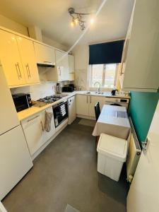 a small kitchen with white cabinets and a sink at Stay and Explore Easy Central London Access via Jubilee Line in London