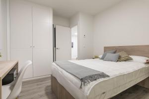 a white bedroom with a large bed and a desk at Micampus Getafe in Getafe