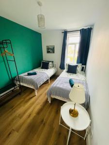 a room with two beds and a table with a lamp at Stay and Explore Easy Central London Access via Jubilee Line in London