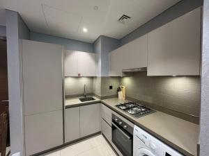 a kitchen with white cabinets and a stove top oven at Prive -Luxury studio in Dubai