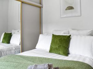 a bedroom with a bed with green pillows and a mirror at Cottage 2 