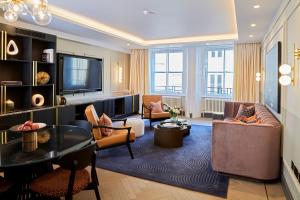 uma sala de estar com uma televisão e um sofá e cadeiras em Cheval Hyde Park Gate em Londres