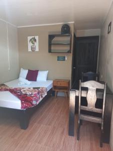 Cette chambre comprend deux lits, une table et une chaise. dans l'établissement Apartamentos Caimán 3, à Tortuguero