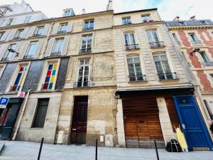 ein altes Gebäude mit bunten Türen und Fenstern in der Unterkunft Dream Dwell Paris- 650m to Notre Dame Apartment near Odéon in Paris
