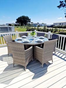 einen Tisch mit Korbstühlen auf einer Terrasse in der Unterkunft Cornwall Caravan Retreat, Near Perranporth, 3 Bedroom in Newquay