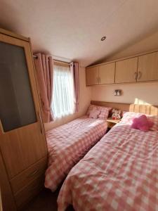 a bedroom with two beds and a flat screen tv at Sea Shore Chalet - Rockley Park in Lytchett Minster
