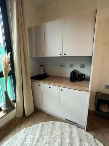 uma cozinha com armários brancos e um lavatório em PHIL & MAX Messe Hotel und Apartments em Hanôver