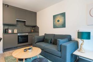 a living room with a blue couch and a table at Serene getaway with terrace on the outskirts of Paris in Montreuil