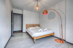 Un dormitorio con una cama y una lámpara. en Le Jungle - Rocade - Grand Place, en Grenoble