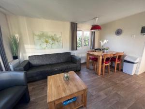 un soggiorno con divano e tavolo di Chalet 102 a Voorthuizen