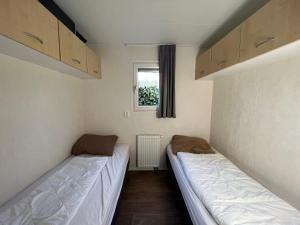 two beds in a small room with a window at Chalet 102 in Voorthuizen