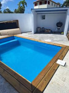 a swimming pool with a wooden deck and blue water at Au Petit Paradis in Saint-François