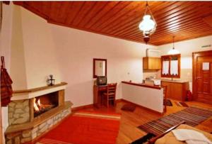 a living room with a fireplace and a kitchen at Andrea Sofi Guesthouse in Dimitsana