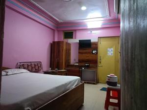 a bedroom with pink walls and a bed and a yellow door at Near Sea Beach Purbasha in Digha