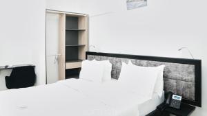 - une chambre avec un lit blanc et un téléphone dans l'établissement SOFT HOTEL, à Douala